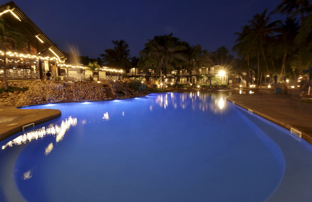 Illuminated swimming pool and tropical grounds at Labadi Beach Hotel in Accra