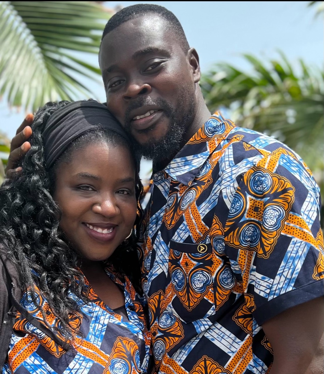 Leandra Wadisons and Leonce Wadison together in coordinated Ghanaian-print clothing beneath palm trees