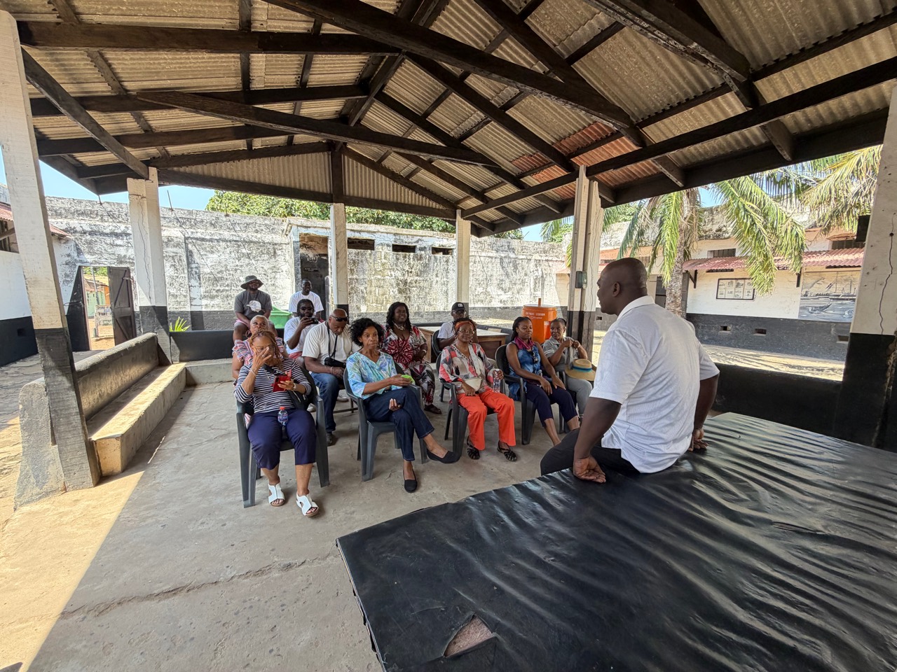 Travelers listening together to a guide at a historic Ghanaian site