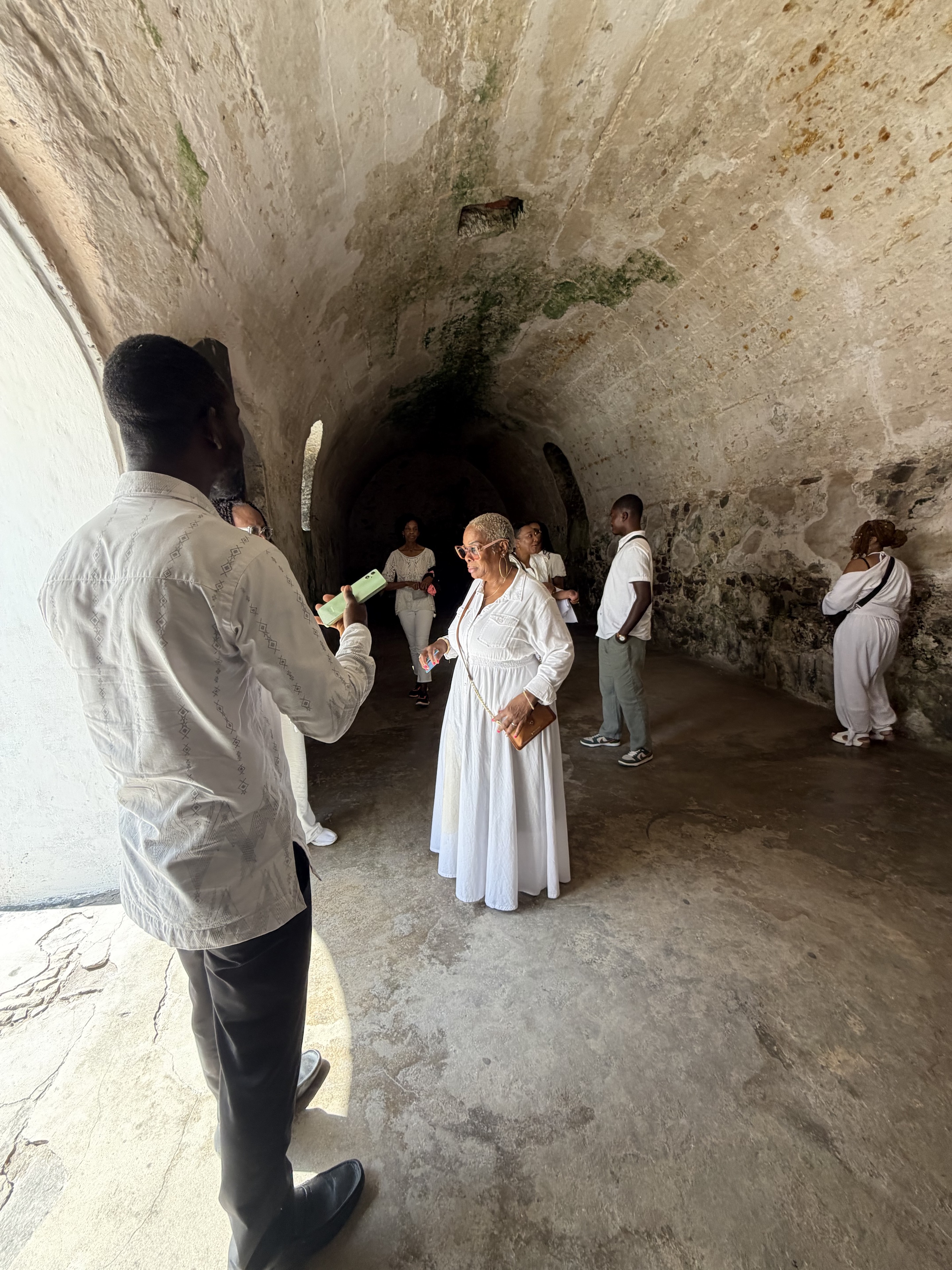 Travelers standing in the vaulted interior of a historic coastal fort in Ghana