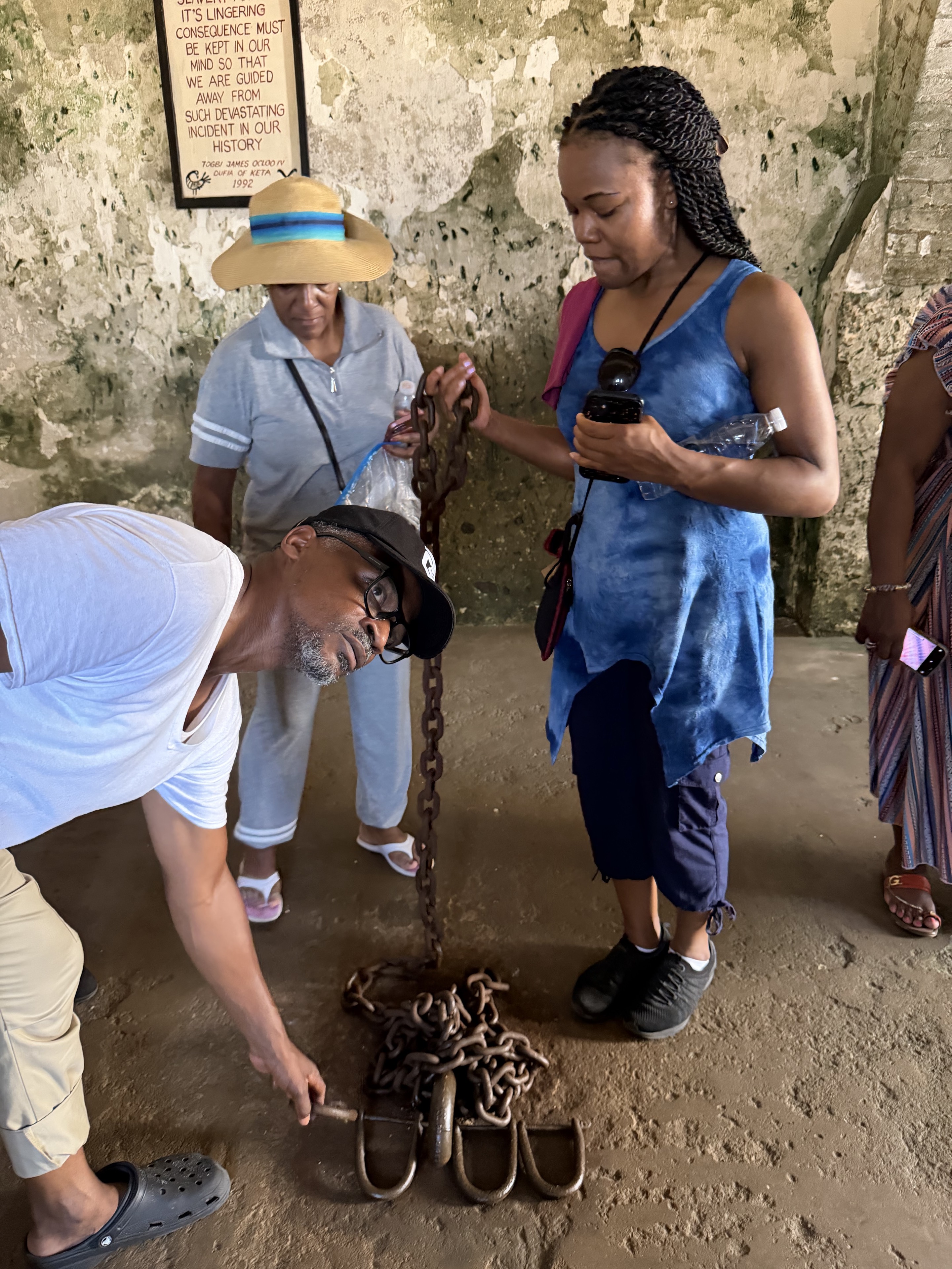 Travelers reflecting on iron restraints inside a historic site during a previous Ghana journey